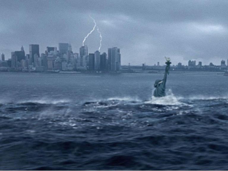 Ein Standbild aus Roland Emerichs Kinofilm "The Day after Tomorrow" zeigt die vom angestiegenen Meeresspiegel untergehende Freiheitsstatue. Im Hintergrund die Skyline von Manhattan unter dramatischem von Blitzen durchzuckten Himmel.