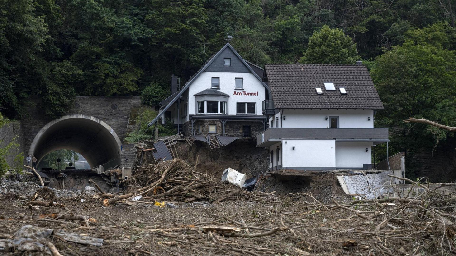 Ein Haus mit der Beschriftung "Am Tunnel", von dem ein großer Teil des Unterschosses und des Hanges, auf dem es steht, weggeschwemmt wurde. Ein Haus mit der Beschriftung "Am Tunnel", von dem ein großer Teil des Unterschosses und des Hanges, auf dem es steht, weggeschwemmt wurde.