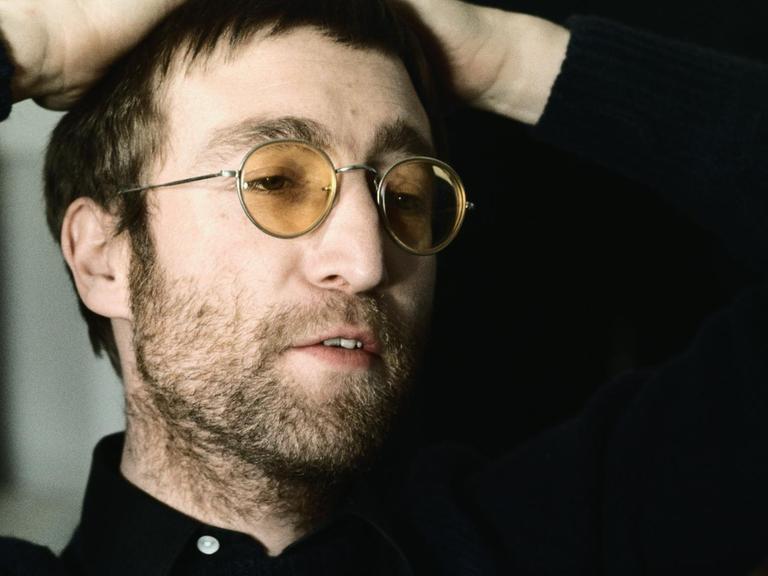 Farbfoto von John Lennon mit Brille mit gelben Gläsern.