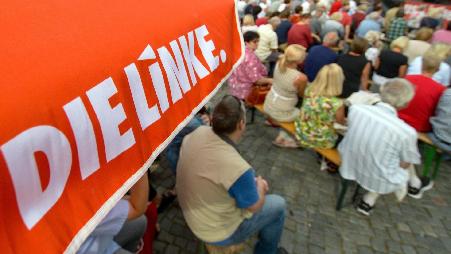 Schweriner Bürger hören in Schwerin bei einer Wahlkampfveranstaltung der Partei Die Linke einer Rede zu.