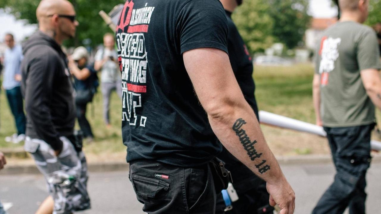 Ein schwarz gekleideter Mann mit einem "Combat 18"-Tattoo am Unterarm läuft neben anderen Männern am 20.07.19 bei einer Demonstration von "Die Rechte" in Kassel