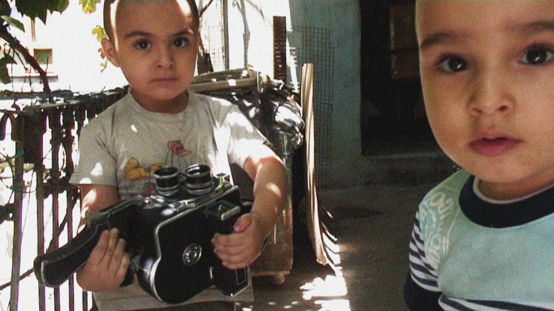 Filmfoto aus "La Dolce Siria" von Ammar al-Beik: Zu sehen sind zwei junge Kinder, von denen eines eine Kamera in den Händen hält. Filmfoto aus "La Dolce Siria" von Ammar al-Beik: Zu sehen sind zwei junge Kinder, von denen eines eine Kamera in den Händen hält.