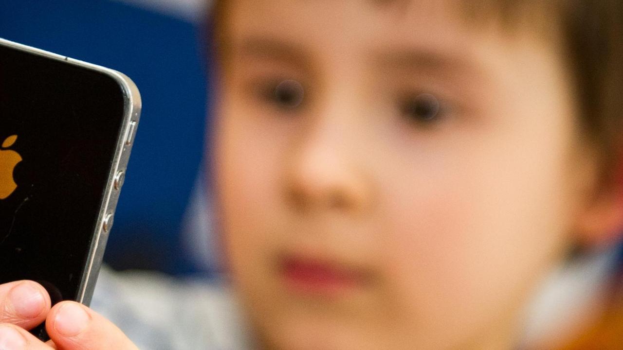 Ein Kind hält ein Smartphone in den Händen. Ein Kind hält ein Smartphone in den Händen.