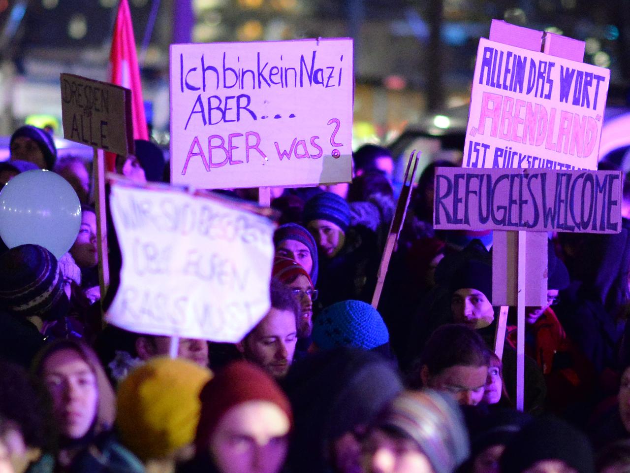Demonstranten der Gegendemonstration zur "Pegida"-Kundgebung halten in Dresden Plakate hoch.