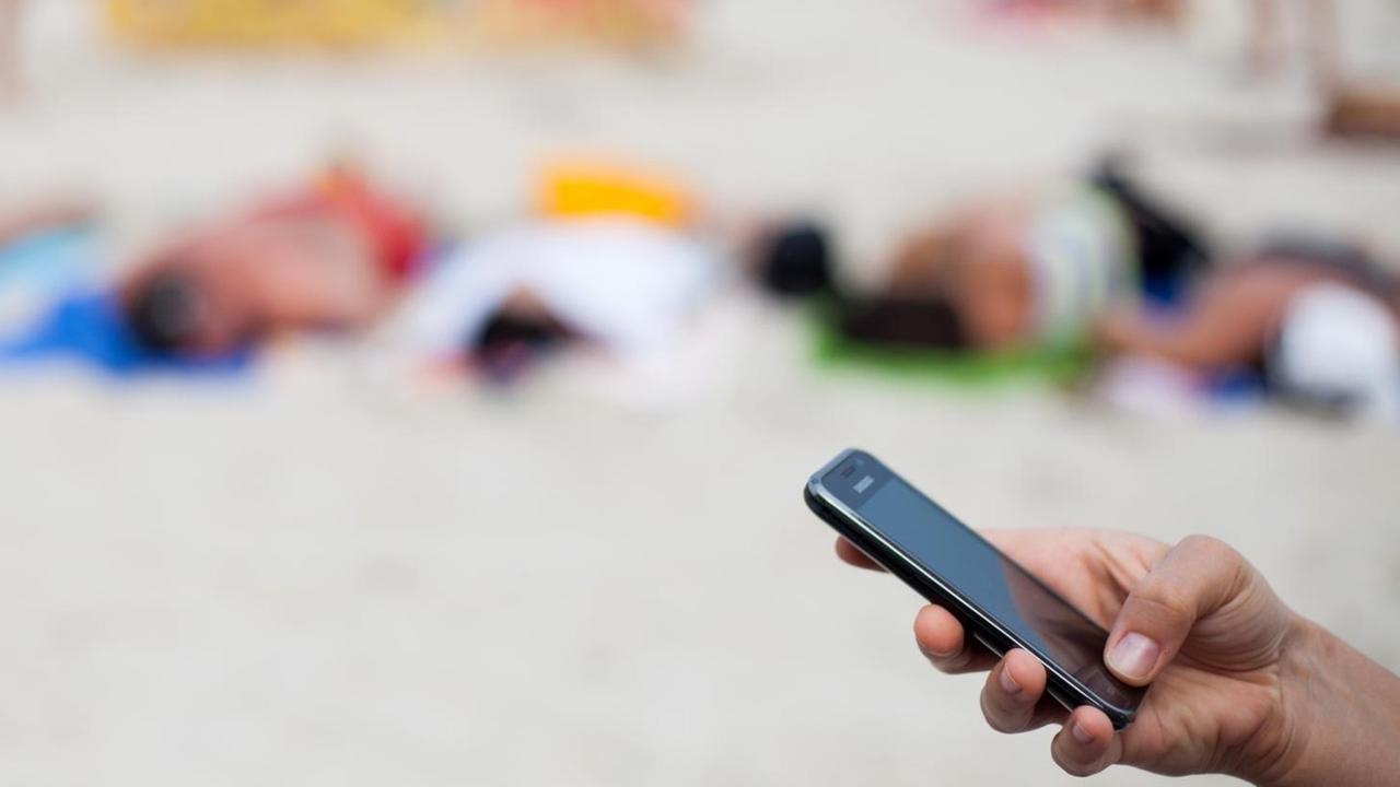 Eine Frau schreibt am 04.08.2013 mit einem Mobiltelefon eine SMS am Strand von Kolberg, Polen, an der Ostsee. Eine Frau schreibt am 04.08.2013 mit einem Mobiltelefon eine SMS am Strand von Kolberg, Polen, an der Ostsee.