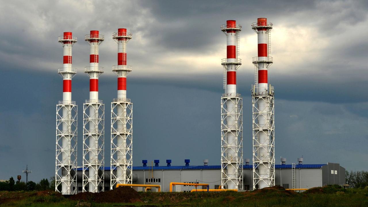 Rot-weiß gestrichene Türme eines Gaskraftwerks vor dunklem Wolkenhimmel. Rot-weiß gestrichene Türme eines Gaskraftwerks vor dunklem Wolkenhimmel.