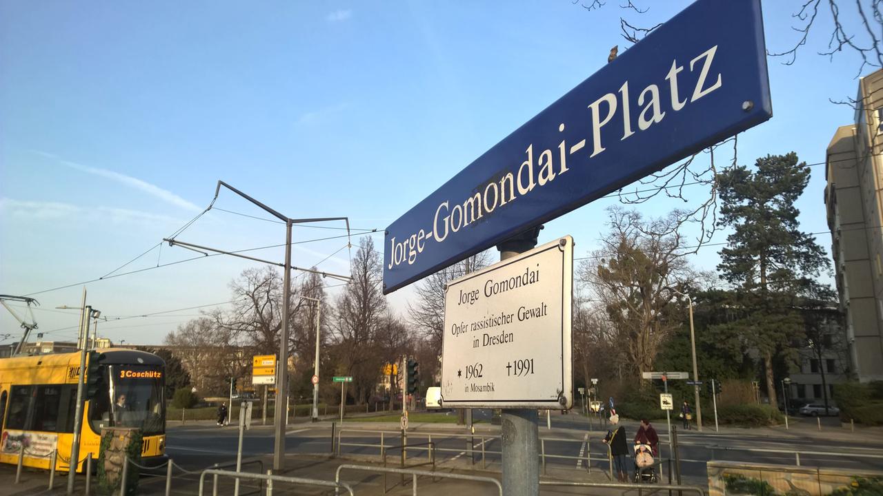 Straßenschild mit der Aufschrift "Jorge-Gomondai-Platz" und darunter "Jorge Gomondai - Opfer rassistischer Gewalt in Dresden; geboren 1962 in Mosambik, gestorben 1991" in Dresden
