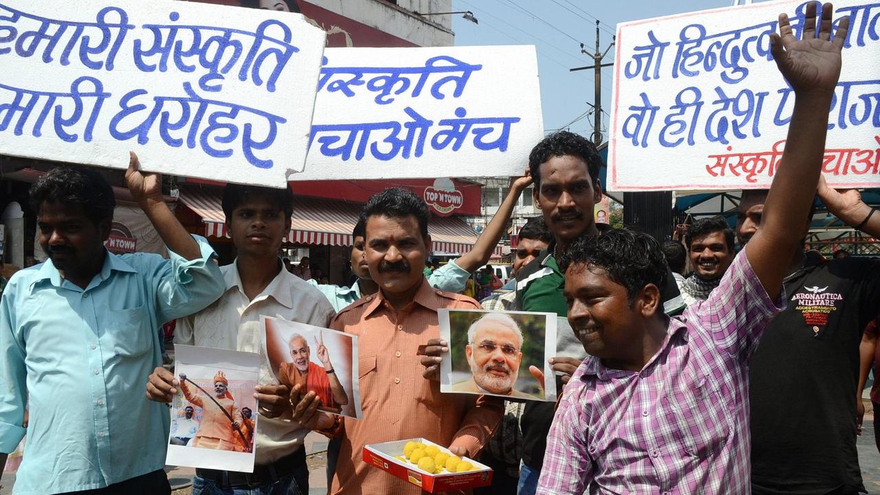 Anhänger der Bharatiya Janata Party (BJP) halten ein Bild des jetzt amtierenden Premierministers Indiens, Narendra Modi, feiern ihn mit Süßigkeiten. Bhopal, Indien, 9. Juni 2013. Die Plakate im Hintergrund von links nach rechts bedeuten: "Unsere Kultur, unser Erbe";"Sanskriti Bachao Manch" (eine Organisation mit dem Ziel die Kultur zu beschützen) und "Wer von Hindutva spricht, wird der Führer des Landes."