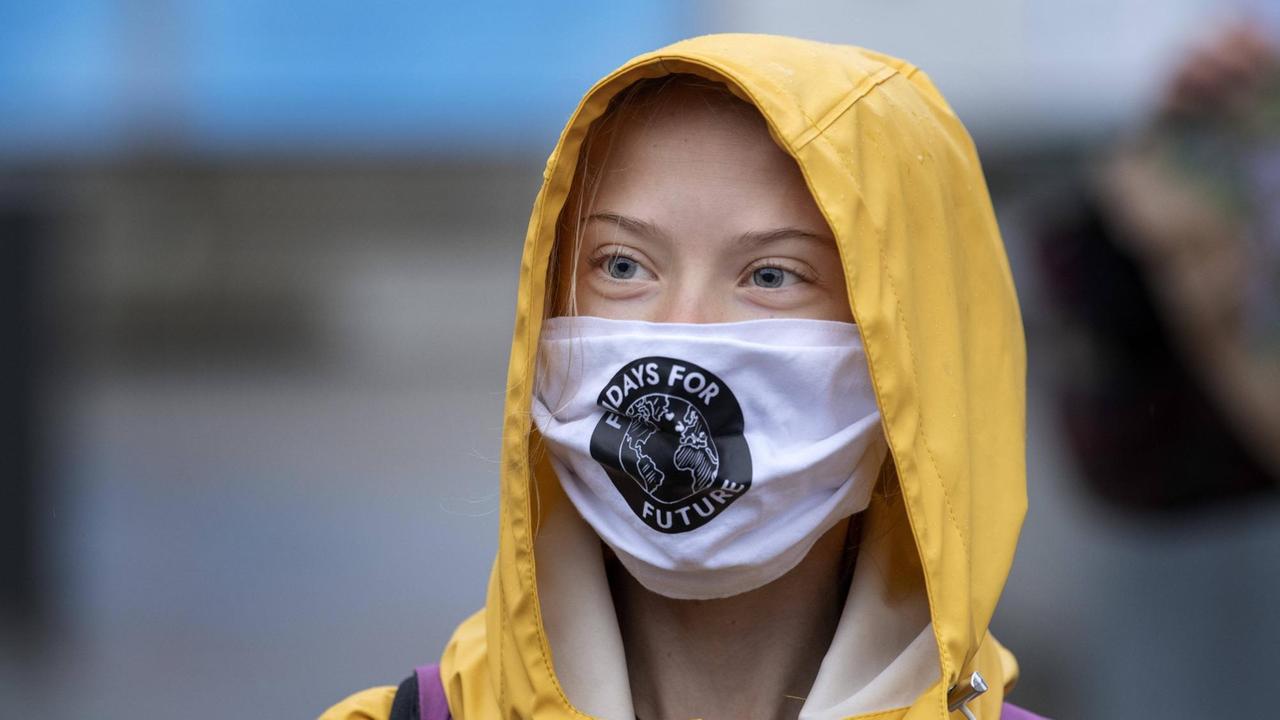 Porträt der schwedischen Klimaaktivistin Greta Thunberg mit Mund-Nasen-Schutz und gelber Regenmantel-Kapuze. Porträt der schwedischen Klimaaktivistin Greta Thunberg mit Mund-Nasen-Schutz und gelber Regenmantel-Kapuze.