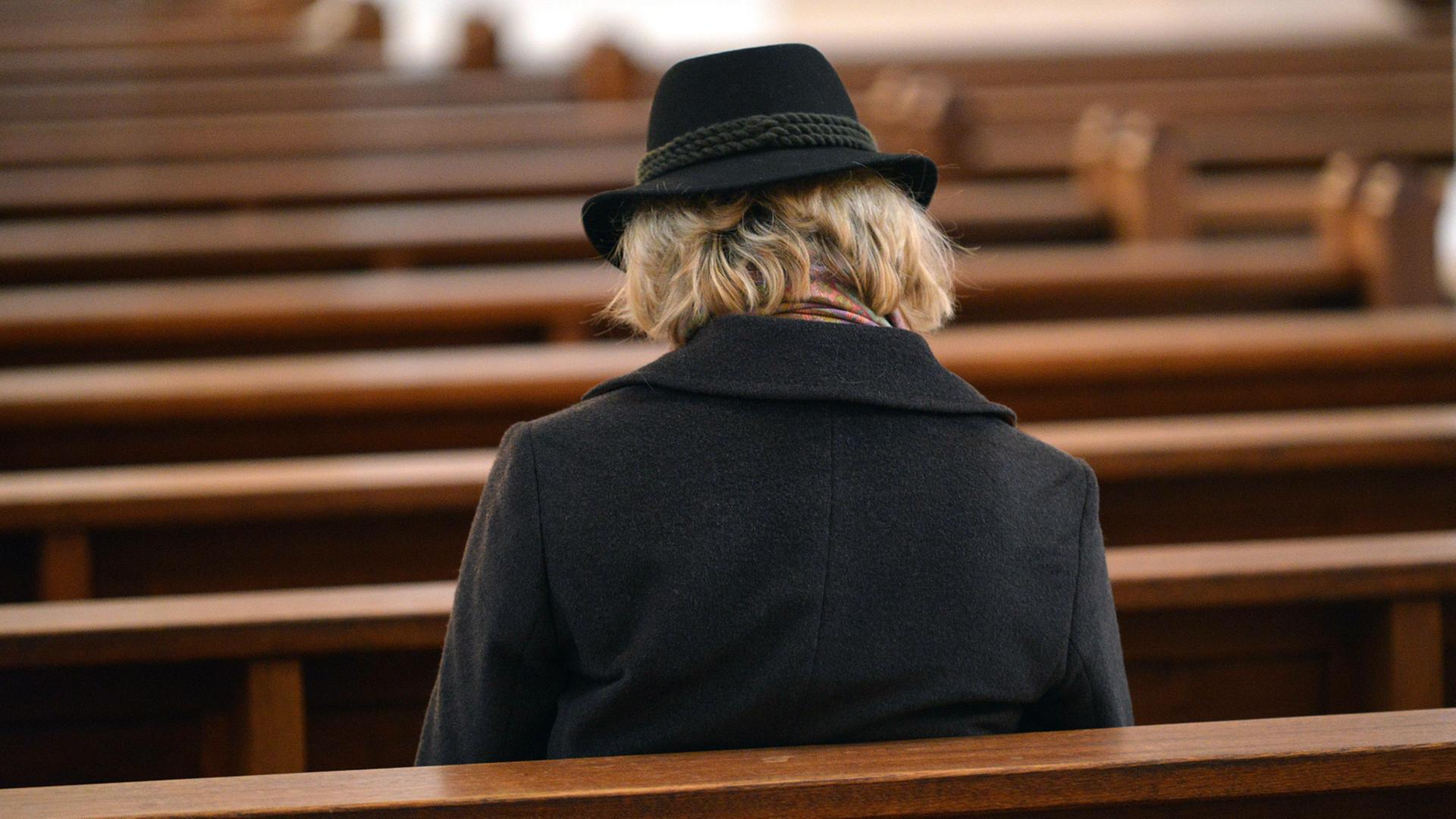 Einzelne Frau auf sonst leeren Kirchenbänken - von Generation zu Generation verliert die Kirche an Bedeutung. Einzelne Frau auf sonst leeren Kirchenbänken - von Generation zu Generation verliert die Kirche an Bedeutung.