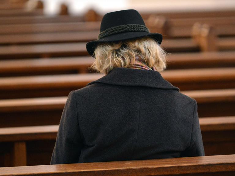 Eine Frau sitzt auf einer Kirchenbank