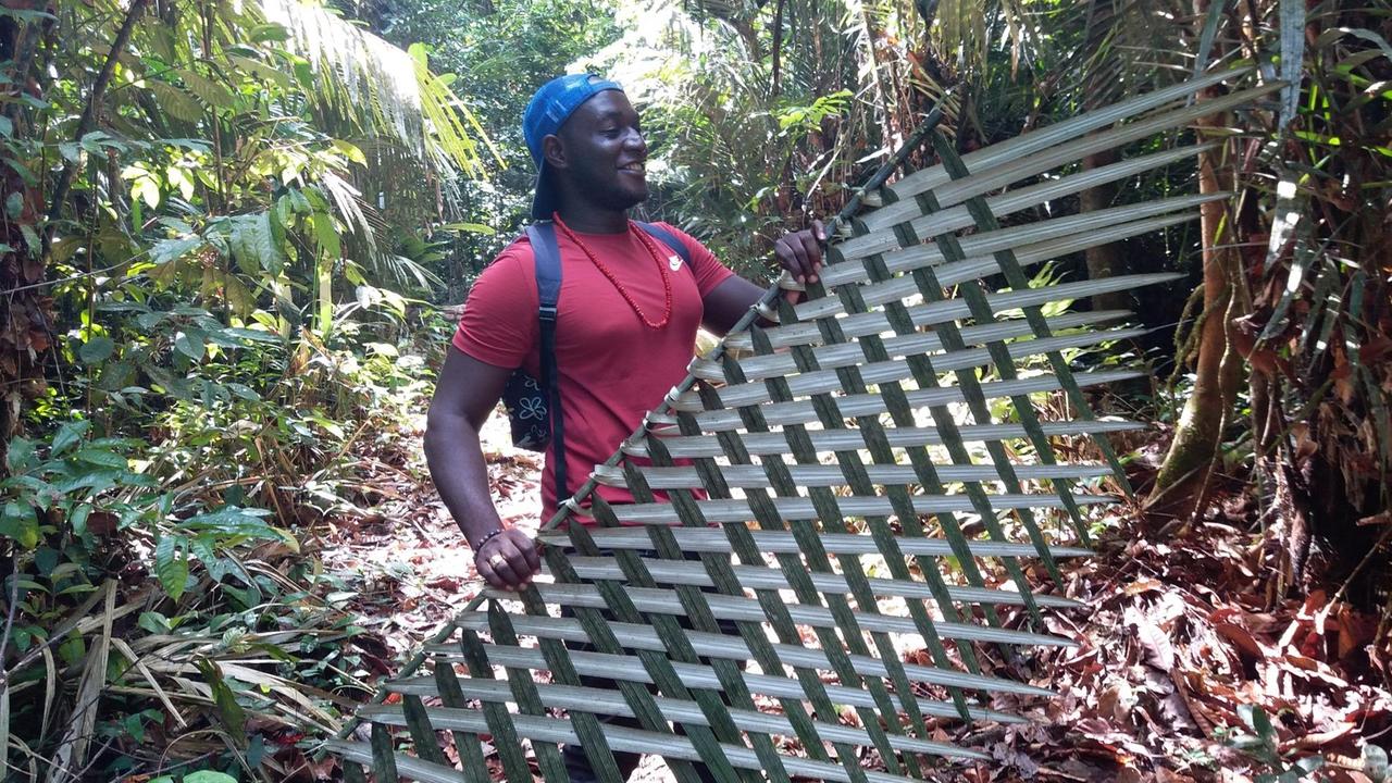 Leon Bodije zeigt den beiden Touristen Peter und Sandra wie aus geflochtenen Palmblättern Sichtschutz hergestellt wird. Leon Bodije zeigt den beiden Touristen Peter und Sandra wie aus geflochtenen Palmblättern Sichtschutz hergestellt wird.