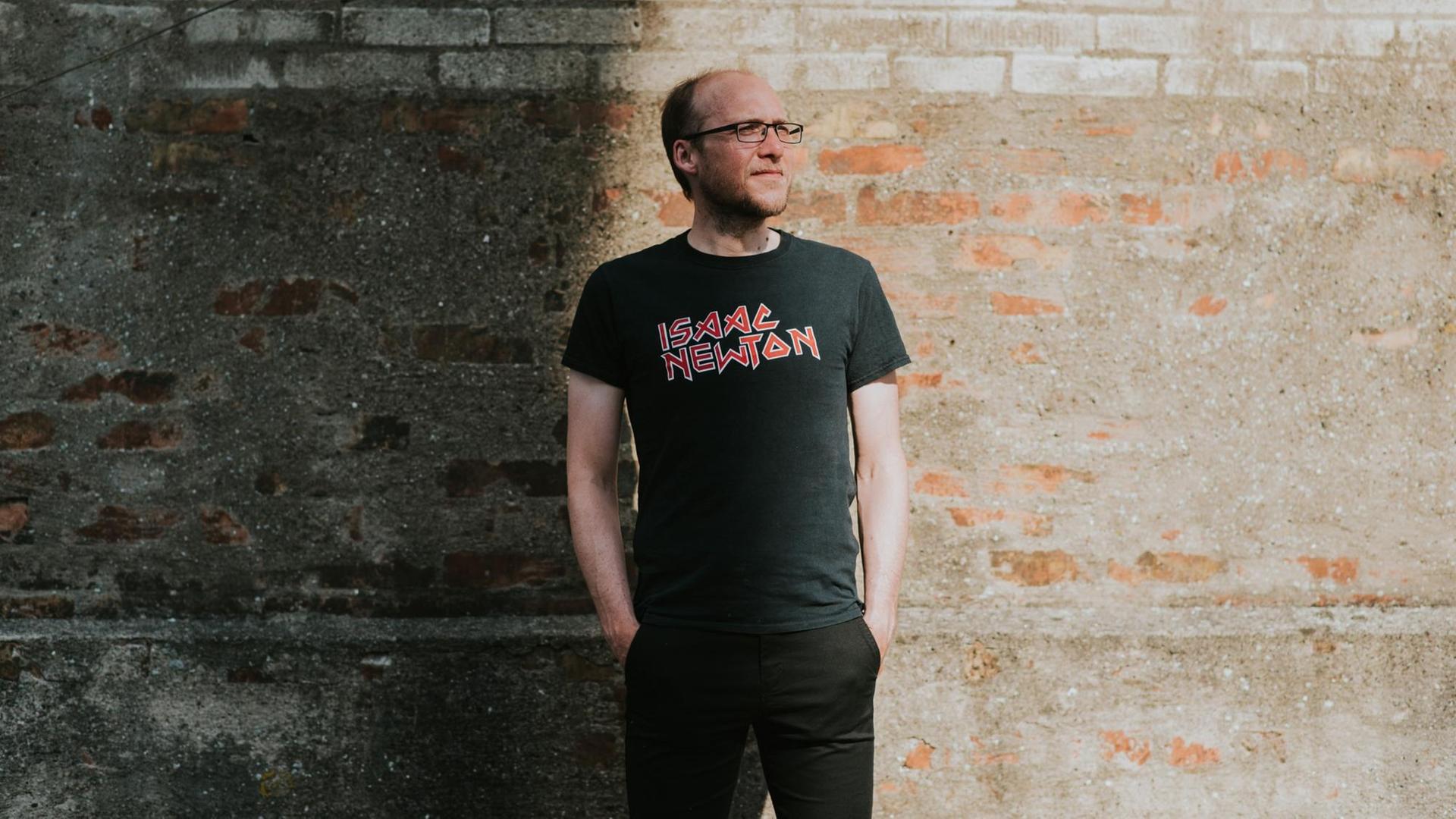 Florian Freistetter steht vor einer Wand und trägt ein "Isaac Newton"-T-Shirt. Florian Freistetter steht vor einer Wand und trägt ein "Isaac Newton"-T-Shirt.