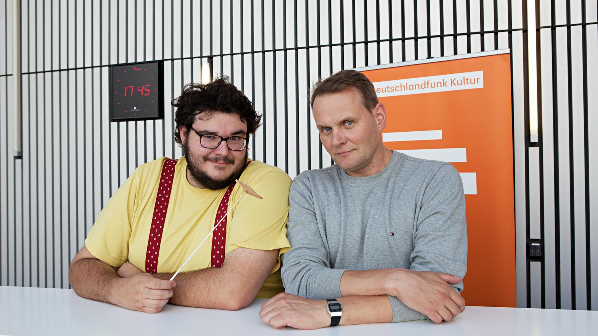 Das Bild zeigt Devid Striesow und Axel Ranisch, die an einem Tisch sitzen.