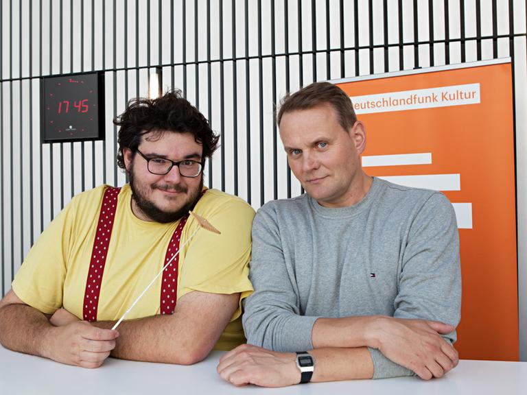Das Bild zeigt Devid Striesow und Axel Ranisch, die an einem Tisch sitzen.