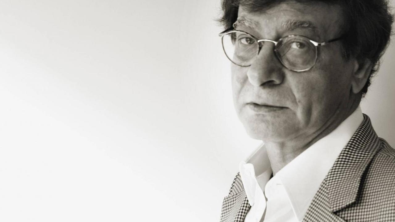 Der palästinensische Lyriker Mahmud Darwish in einem Schwarzweißfoto. Er trägt einen grauen Anzug. Der palästinensische Lyriker Mahmud Darwish in einem Schwarzweißfoto. Er trägt einen grauen Anzug.