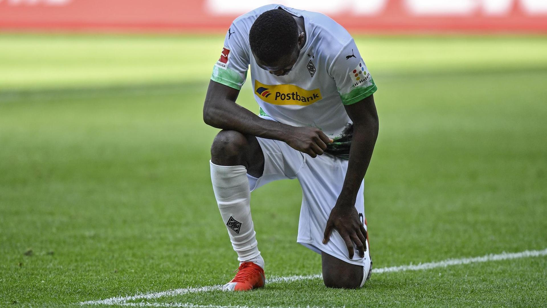 Das Foto zeigt den Fußballer Marcus Thuram von Borussia Mönchengladbach. Er kniet nach einem Treffer und setzt damit ein Zeichen gegen Rassismus. Das Foto zeigt den Fußballer Marcus Thuram von Borussia Mönchengladbach. Er kniet nach einem Treffer und setzt damit ein Zeichen gegen Rassismus.