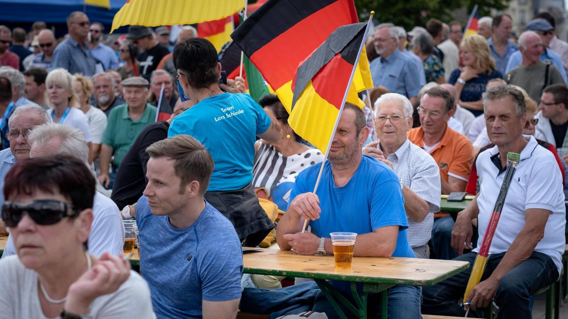 Beim AfD-Wahlkampfauftakt in Brandenburg sitzen Teilnehmer teilweise mit Deutschlandfahnen auf Bierbänken und warten auf die Redner. Beim AfD-Wahlkampfauftakt in Brandenburg sitzen Teilnehmer teilweise mit Deutschlandfahnen auf Bierbänken und warten auf die Redner.