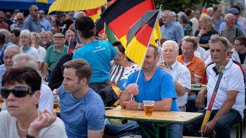 Beim AfD-Wahlkampfauftakt in Brandenburg sitzen Teilnehmer teilweise mit Deutschlandfahnen auf Bierbänken und warten auf die Redner.