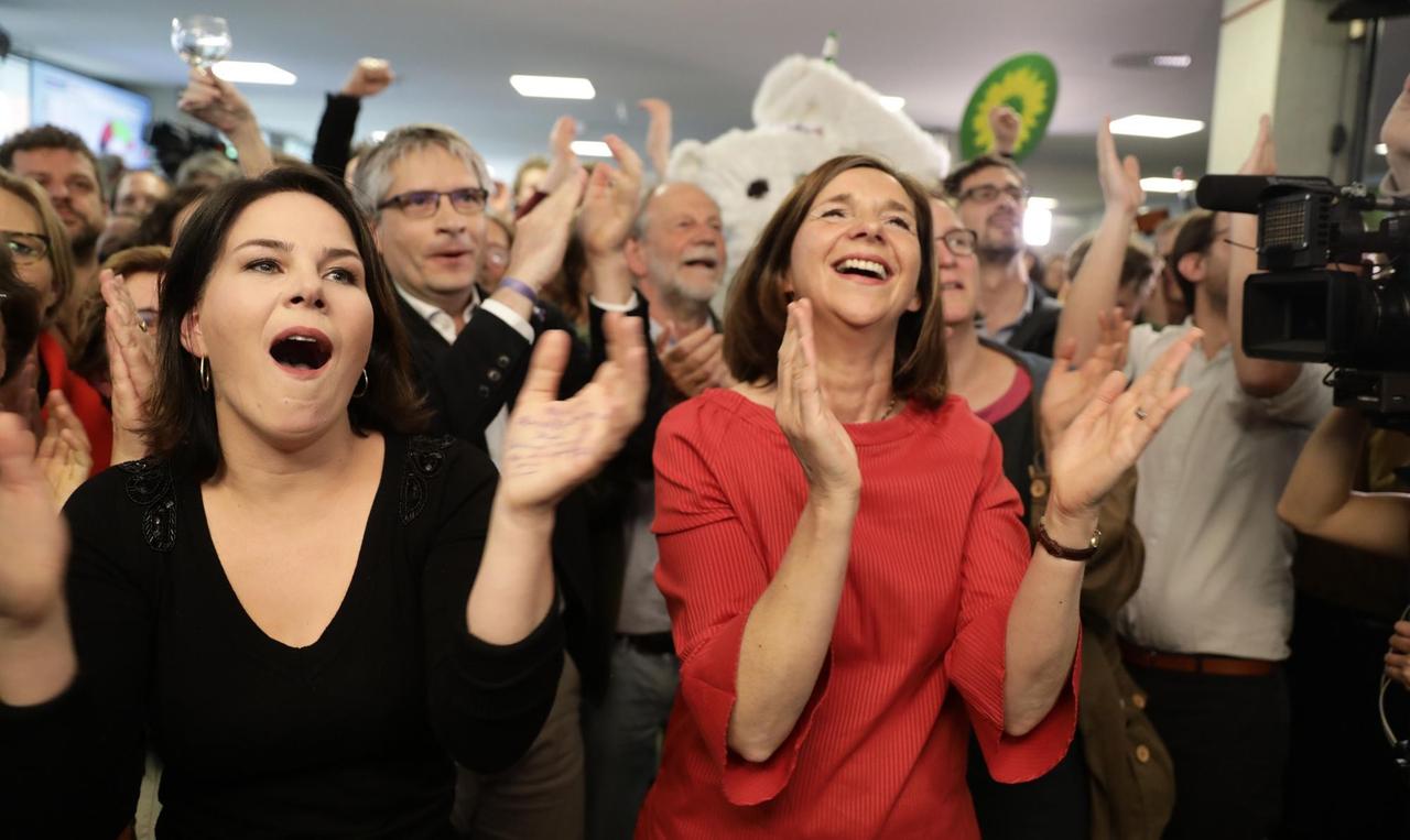 Die Grünen-Spitzenpolitiker Annalena Baerbock, Katrin Göring-Eckard und Sven Giegold jubeln und klatschen gemeinsam mit Parteifreund*innen. Die Grünen-Spitzenpolitiker Annalena Baerbock, Katrin Göring-Eckard und Sven Giegold jubeln und klatschen gemeinsam mit Parteifreund*innen.