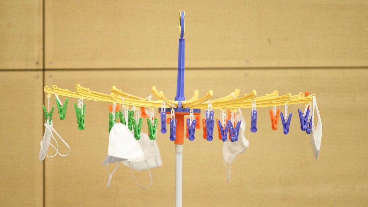 Fotografie eines runden Wäscheständers auf dem Schutzmasken hängen. Fotografie eines runden Wäscheständers auf dem Schutzmasken hängen.