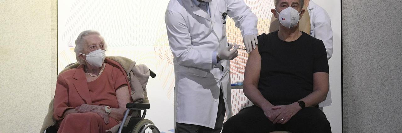 Emilie Repikova (links),Veteranin des Zweiten Weltkriegs, beobachtet wie Andrej Babis, Premierminister von Tschechien, im Zentralen Militärkrankenhaus mit dem Corona-Impfstoff geimpft wird. Emilie Repikova (links),Veteranin des Zweiten Weltkriegs, beobachtet wie Andrej Babis, Premierminister von Tschechien, im Zentralen Militärkrankenhaus mit dem Corona-Impfstoff geimpft wird.