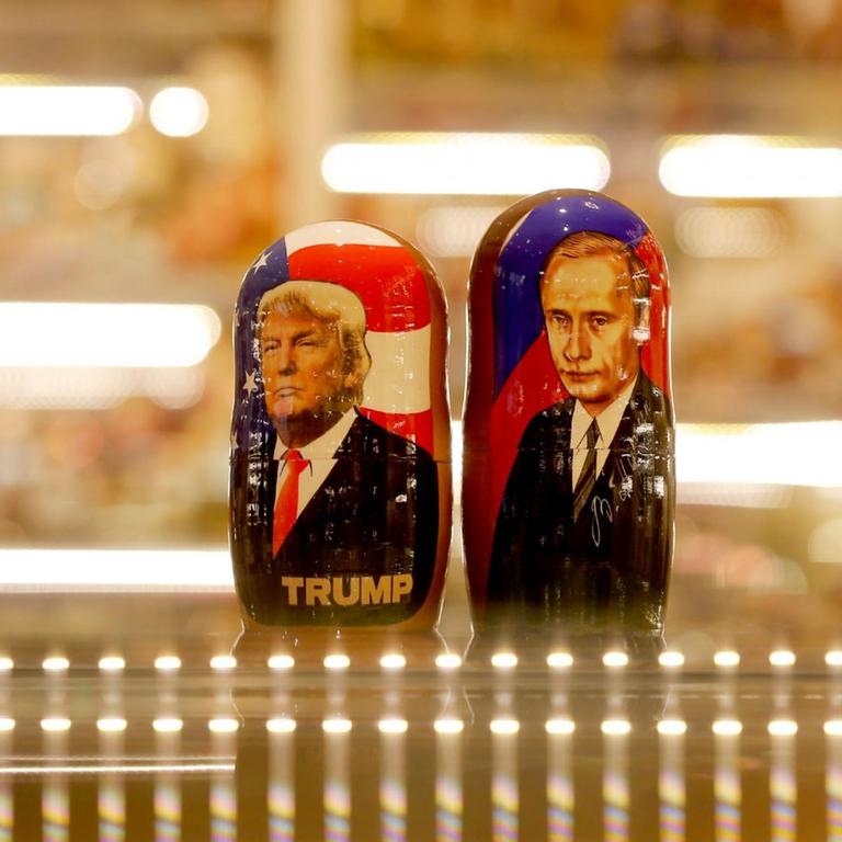 Zwei bemalte Matroschka-Puppen von Wladimir Putin und Donald Trump auf der gläsernen Theke eines Souvenirgeschäft.