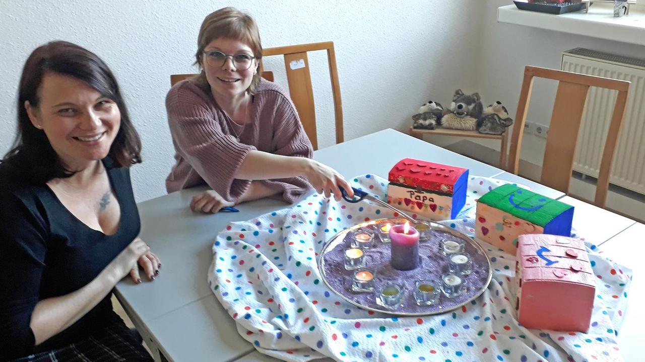 Die Trauerbegleiterinnen Katrin und Daniela vom Verein Wolfsträne in Leipzig. Zwei Frauen sitzen an einem Tisch und zünden Teelichter an. Die Trauerbegleiterinnen Katrin und Daniela vom Verein Wolfsträne in Leipzig. Zwei Frauen sitzen an einem Tisch und zünden Teelichter an.