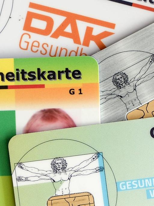 Versichertenkarten (AOK, TK, BarmerGEK, DAK) liegen übereinander.