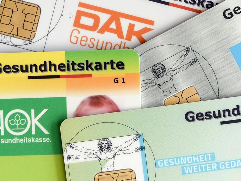 Versichertenkarten (AOK, TK, BarmerGEK, DAK) liegen übereinander.