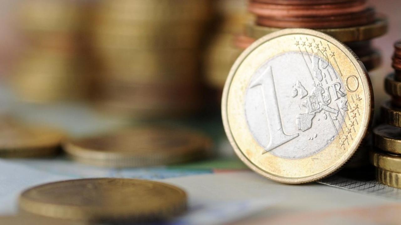 Eine 1-Euro-Münze lehnt am 04.11.2014 in München (Bayern) an gestapelten Münzen.