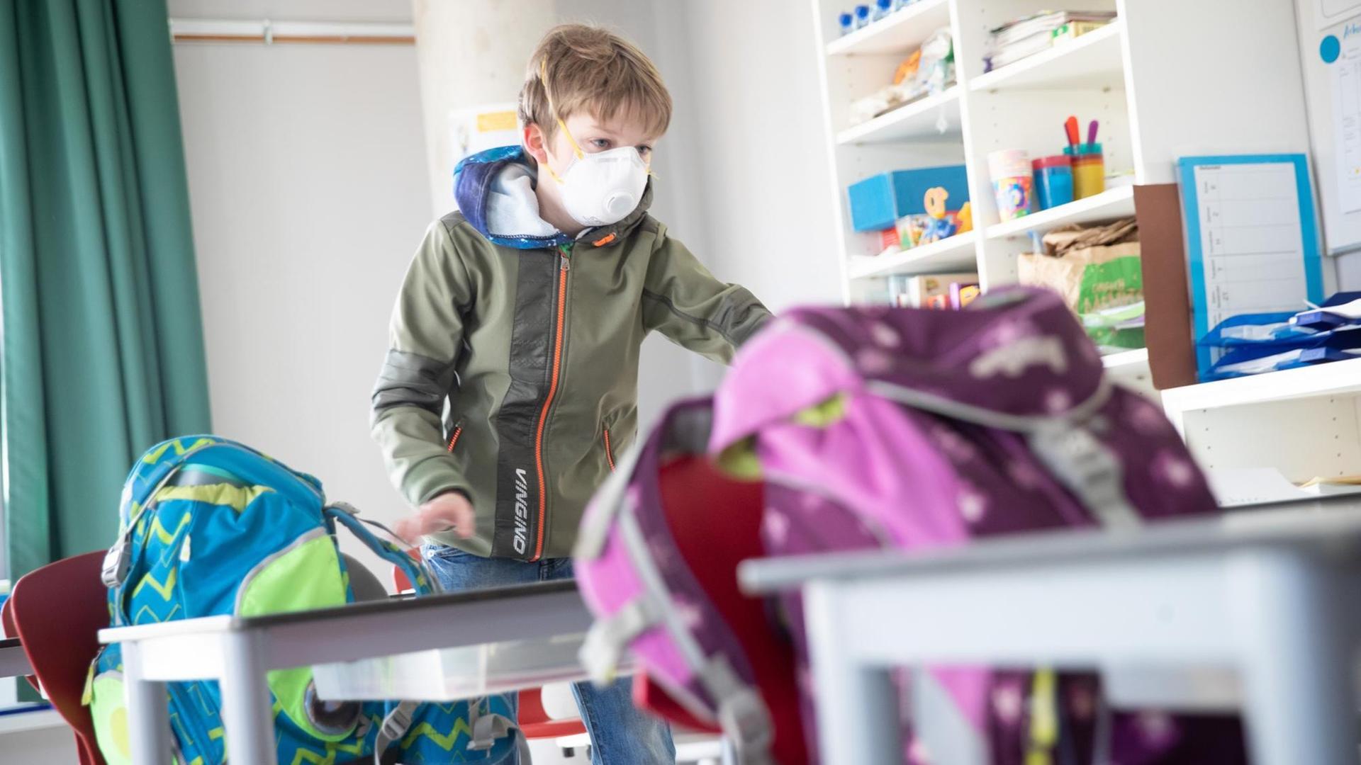 Ein Schüler der Klasse 4d in der Goldbeck-Schule kommt mit Mundschutz in die Klasse und stellt seine Schulranzen auf seinen Tisch. Ein Schüler der Klasse 4d in der Goldbeck-Schule kommt mit Mundschutz in die Klasse und stellt seine Schulranzen auf seinen Tisch.