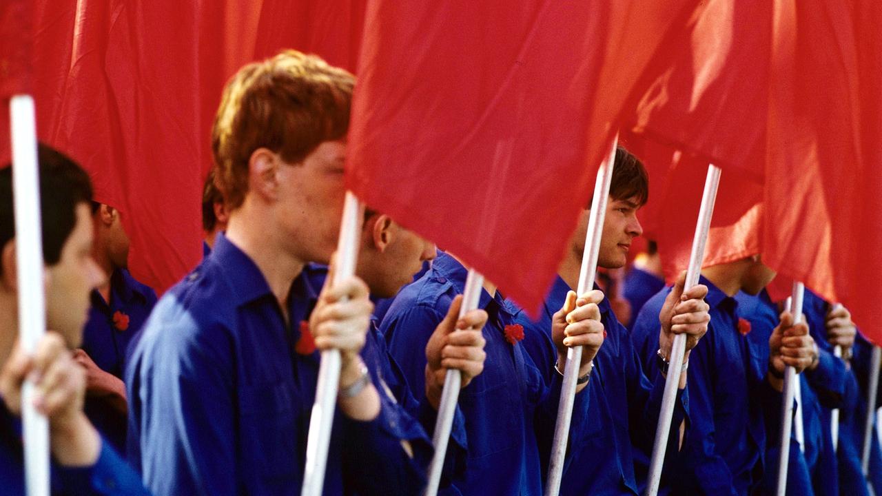 Mit roten Arbeiterfahnen stehen Mitglieder der FDJ in Berlin im April 1981 am Palast der Republik, der Tagungsstätte des X. Parteitages der SED. Mit roten Arbeiterfahnen stehen Mitglieder der FDJ in Berlin im April 1981 am Palast der Republik, der Tagungsstätte des X. Parteitages der SED.