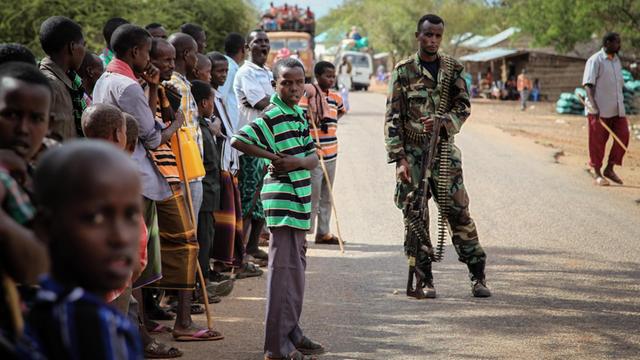 Bewohner der rund 40 Kilometer von Baidoa entfernt gelegenen Ortschaft Modmoday stehen neben einem somalischen Soldaten an einer Straße.