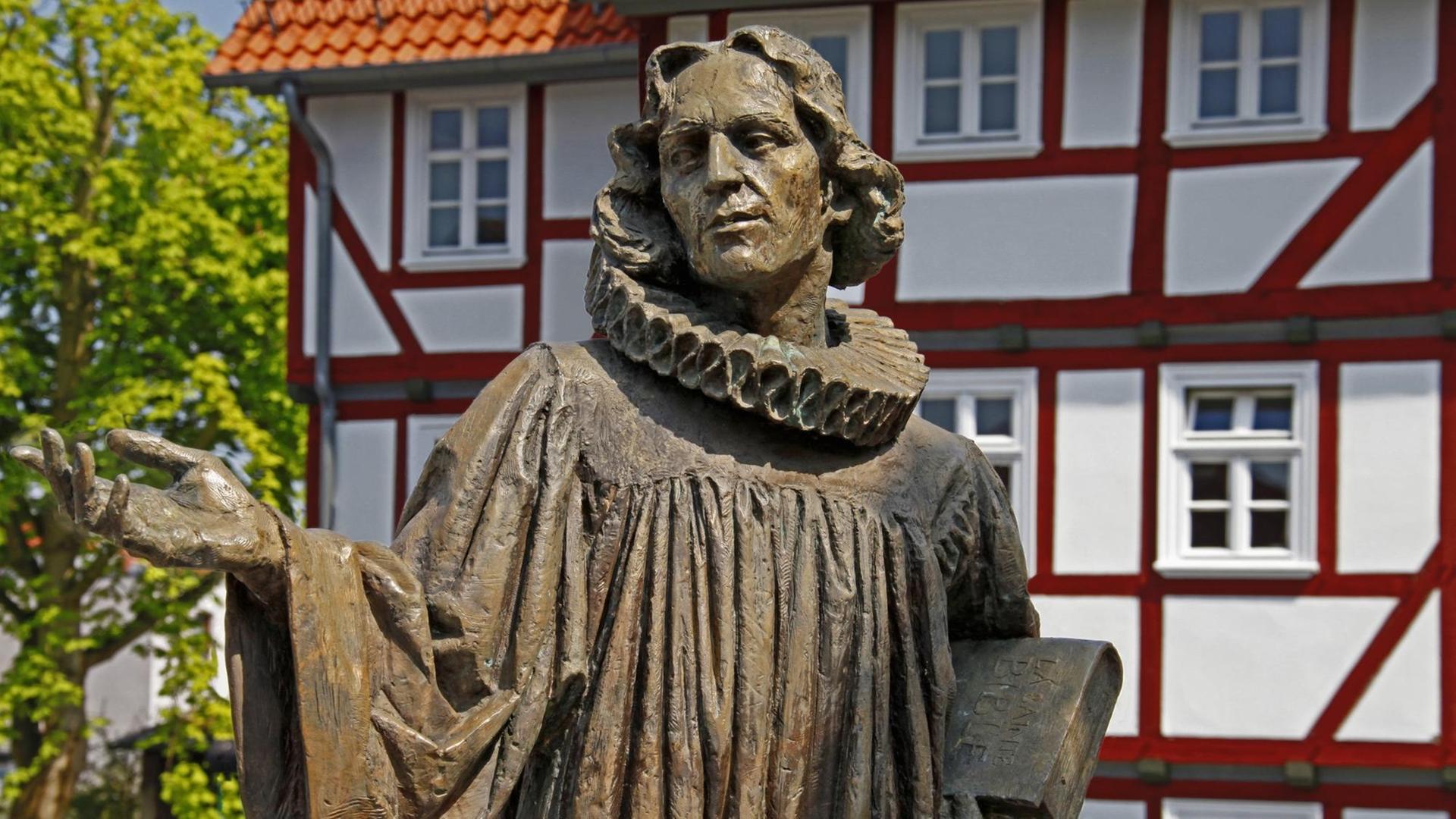 Statue von David Clément vor einem Fachwerkhaus. Statue von David Clément vor einem Fachwerkhaus.