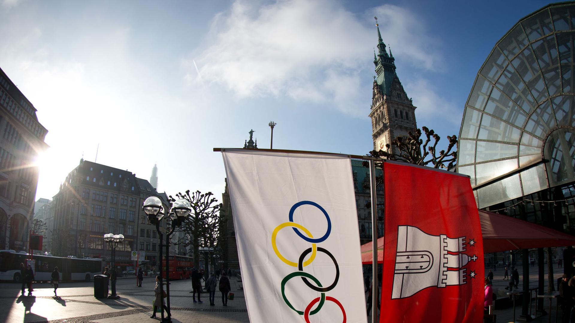 Flaggen mit den Olympischen Ringen und dem Wappen von Hamburg hängen neben einem Straßencafe am Rathausmarkt in Hamburg Flaggen mit den Olympischen Ringen und dem Wappen von Hamburg hängen neben einem Straßencafe am Rathausmarkt in Hamburg
