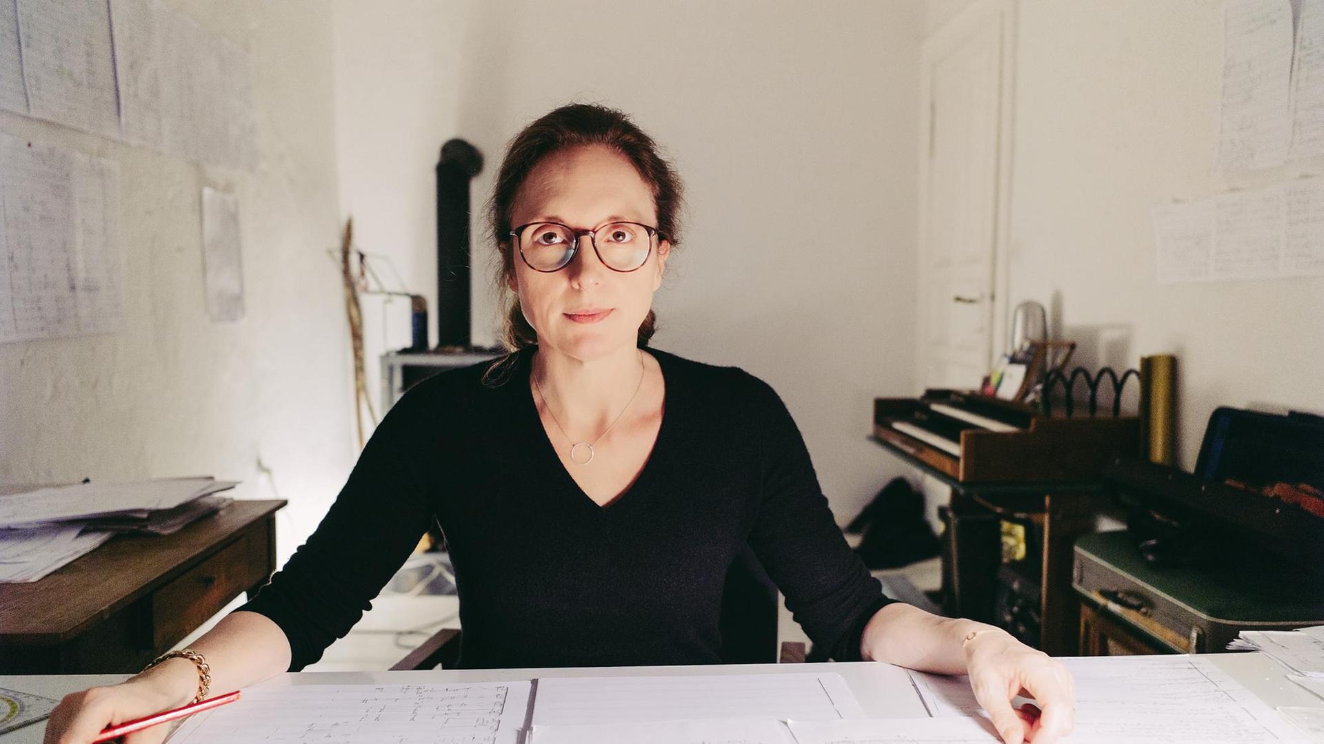 Rebecca Saunders sitzt in einem Arbeitszimmer an einem Schreibtisch Rebecca Saunders sitzt in einem Arbeitszimmer an einem Schreibtisch