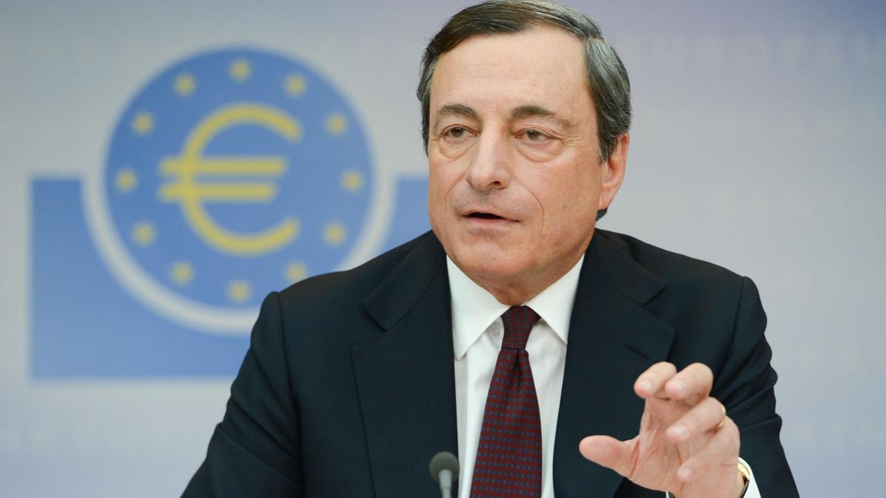 Mario Draghi spricht und gestikuliert mit der Hand vor einer Wand mit dem Logo der EZB.