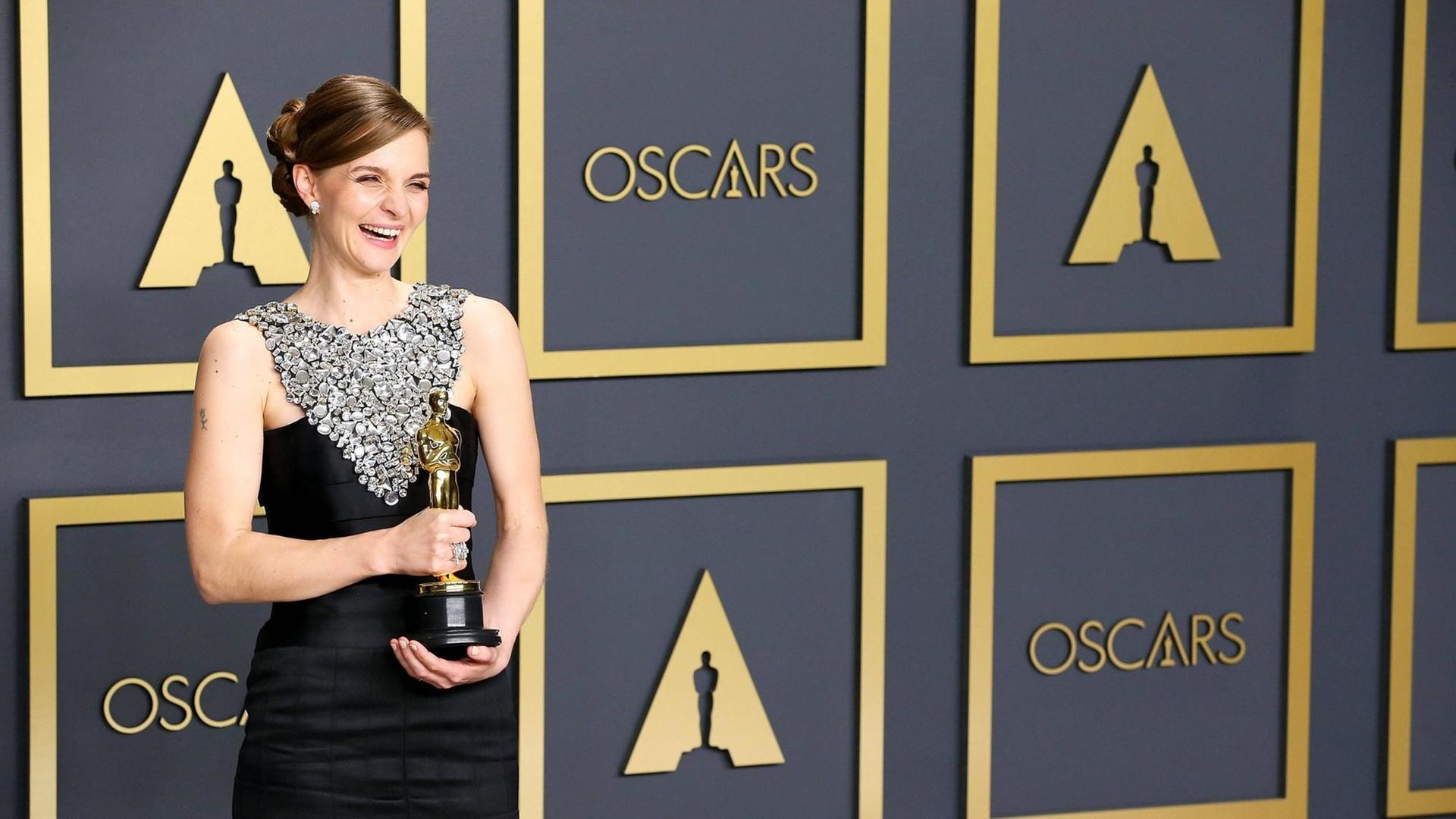 Hildur Gudnadottir im dunklen Kleid mit ihrem Oscar für die beste Filmmusik. Hildur Gudnadottir im dunklen Kleid mit ihrem Oscar für die beste Filmmusik.