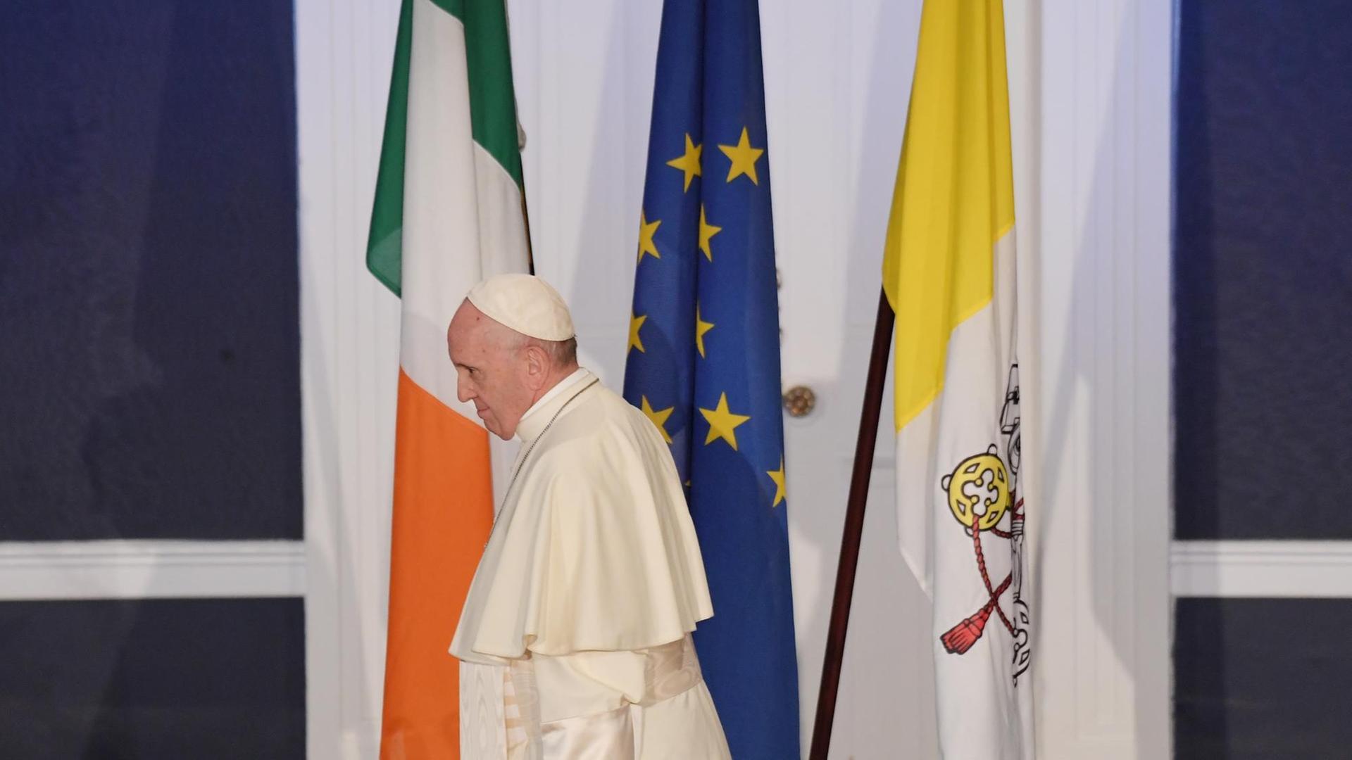 Papst Franziskus geht während seiner ersten Rede im irischen Dublin an drei Flaggen vorüber, der irischen (links), der europäischen (Mitte) und der des Vatikan (rechts). Papst Franziskus geht während seiner ersten Rede im irischen Dublin an drei Flaggen vorüber, der irischen (links), der europäischen (Mitte) und der des Vatikan (rechts).