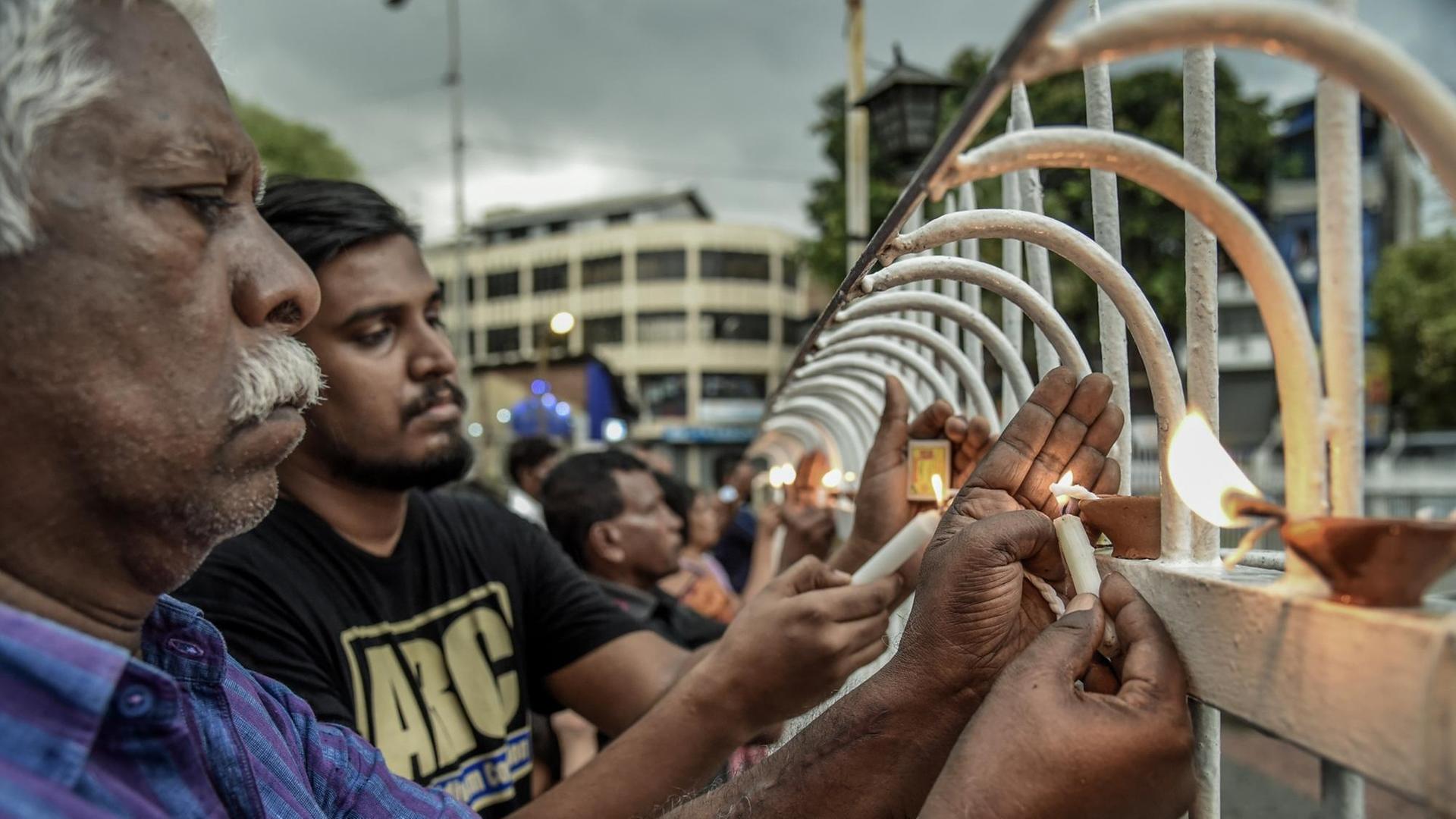 Trauernde Menschen aus Sri Lanka zünden am 23. April 2019 in der Nähe der Kirche St. Anthony in Colombo Kerzen für die Terroropfer vom Ostersonntag an.
