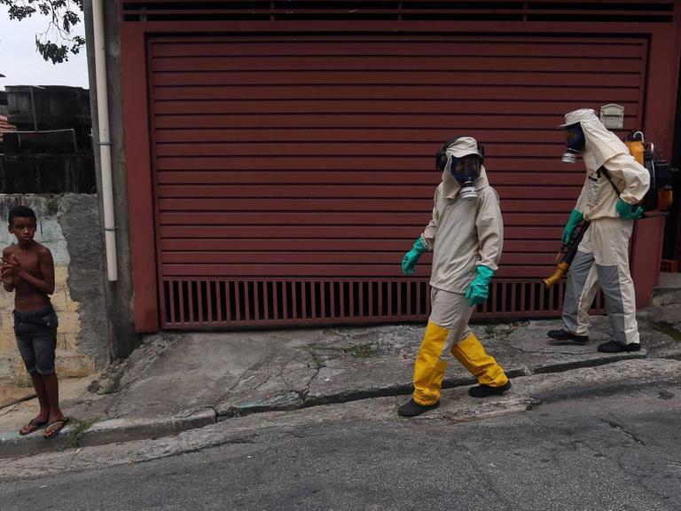 Helfer mit Gasmasken laufen durch die Straßen von Sao Paulo.