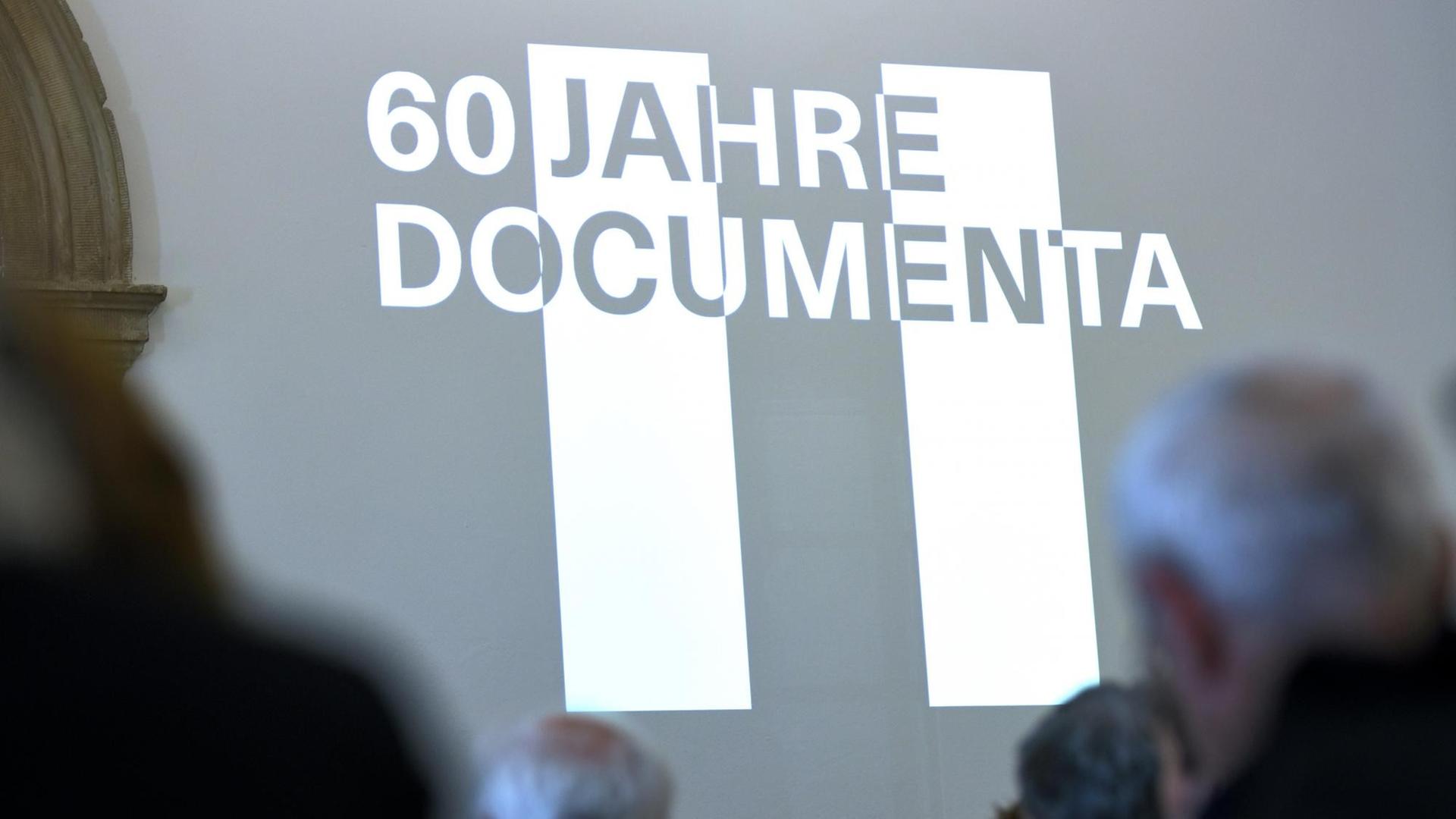 Der Schriftzug "60 Jahre documenta" erscheint als Licht-Bild an einer Museums-Wand.