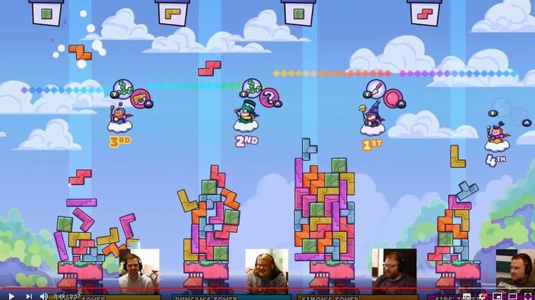 Szene aus dem Gemeinschaftscomputerspiel "Tricky Towers". Vier Spieler und Spielerinnen bauen virtuell Steine übereinander zu einem Turm.