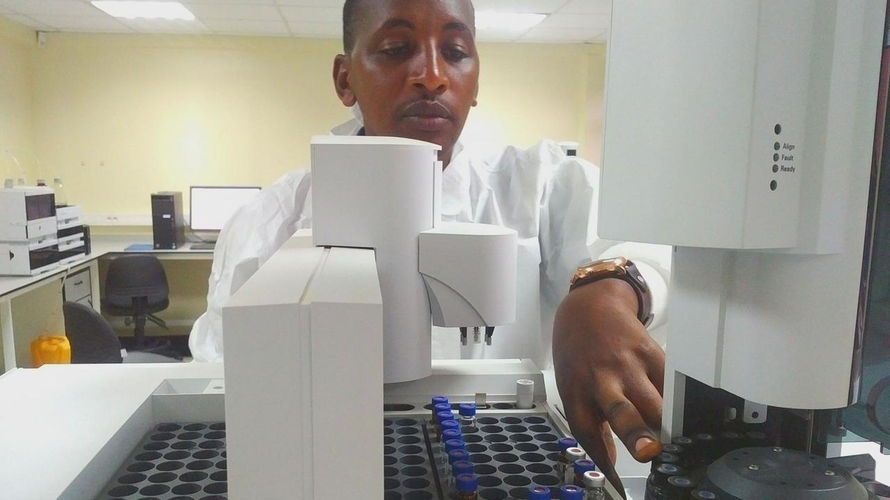 Ein Labormitarbeiter im weißen Kittel nimmt ein Röhrchen mit einer DNA-Probe aus einem Behälter.
