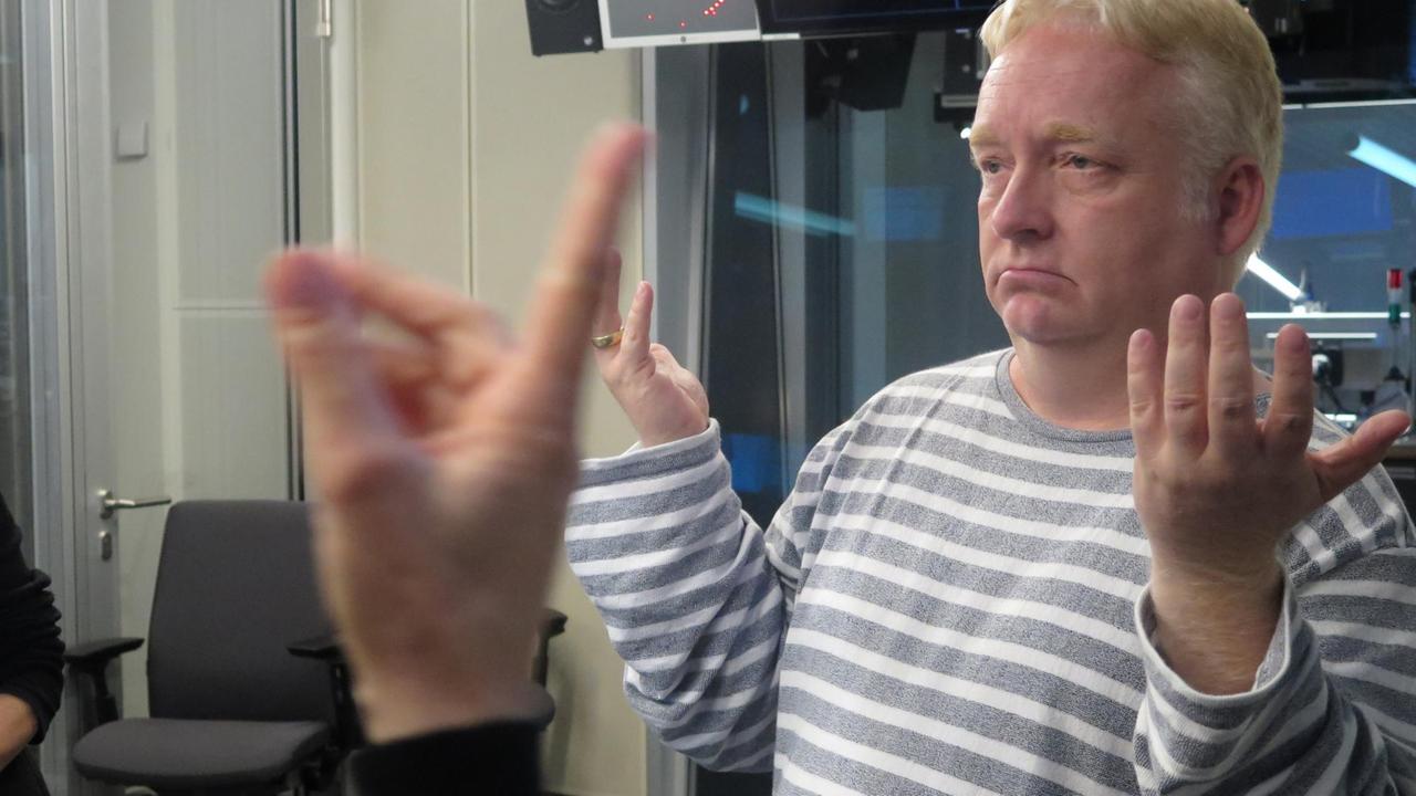 Christian Rathmann, Professor für Gebärdensprachdolmetschen, bei "Studio 9". Mittels Dolmetscherin gibt der gehörlose Linguist das Interview. Christian Rathmann, Professor für Gebärdensprachdolmetschen, bei "Studio 9". Mittels Dolmetscherin gibt der gehörlose Linguist das Interview.