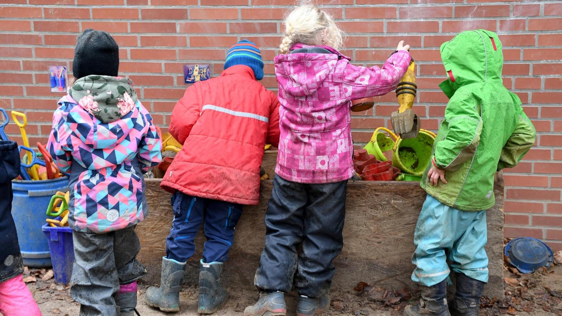 Das Foto zeigt Kita-Kinder, die draußen im Matsch spielen. Das Foto zeigt Kita-Kinder, die draußen im Matsch spielen.