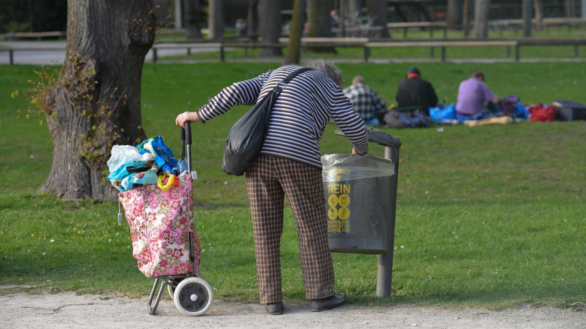 Eine alte Frau sammelt Pfandflaschen aus einem Mülleimer. Eine alte Frau sammelt Pfandflaschen aus einem Mülleimer.