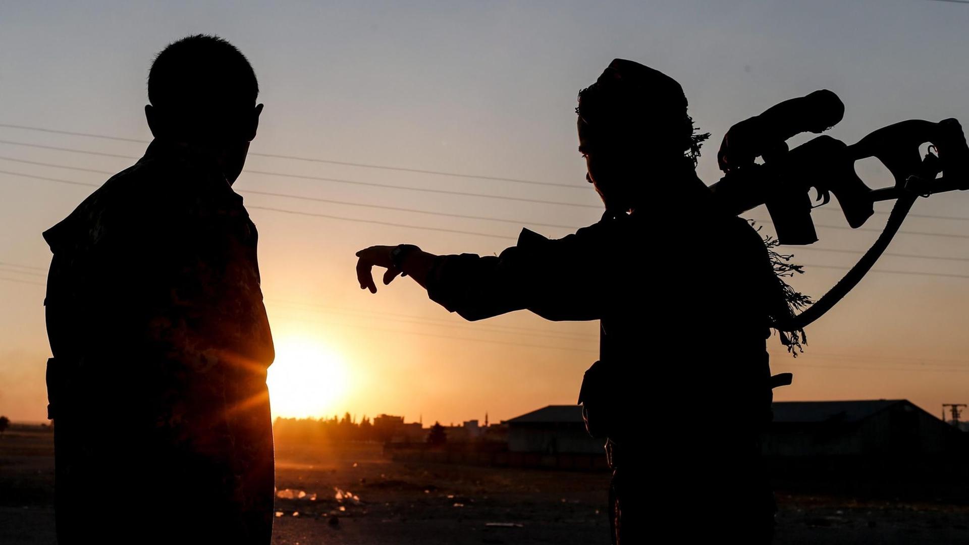 Zwei Mitglieder der kurdischen YPG-Truppen blicken auf den Sonnenuntergang beim Grenzübergang Tel Abyad in Nord-Syrien. Zwei Mitglieder der kurdischen YPG-Truppen blicken auf den Sonnenuntergang beim Grenzübergang Tel Abyad in Nord-Syrien.