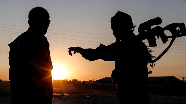 Zwei Mitglieder der kurdischen YPG-Truppen blicken auf den Sonnenuntergang beim Grenzübergang Tel Abyad in Nord-Syrien.
